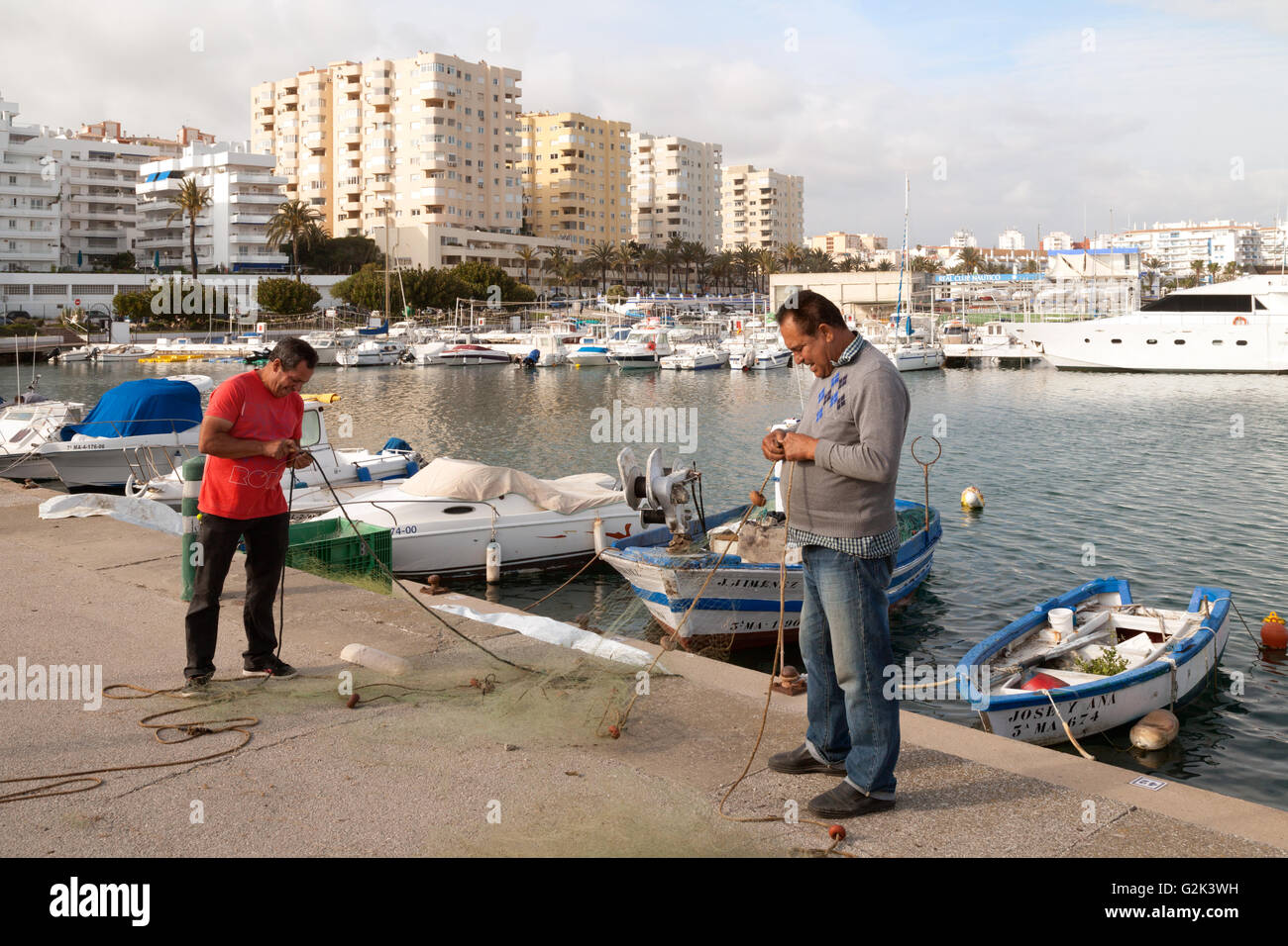 Spanish fishermen repairing their fishing nets, Estepona harbour, Andalusia Spain Europe Stock