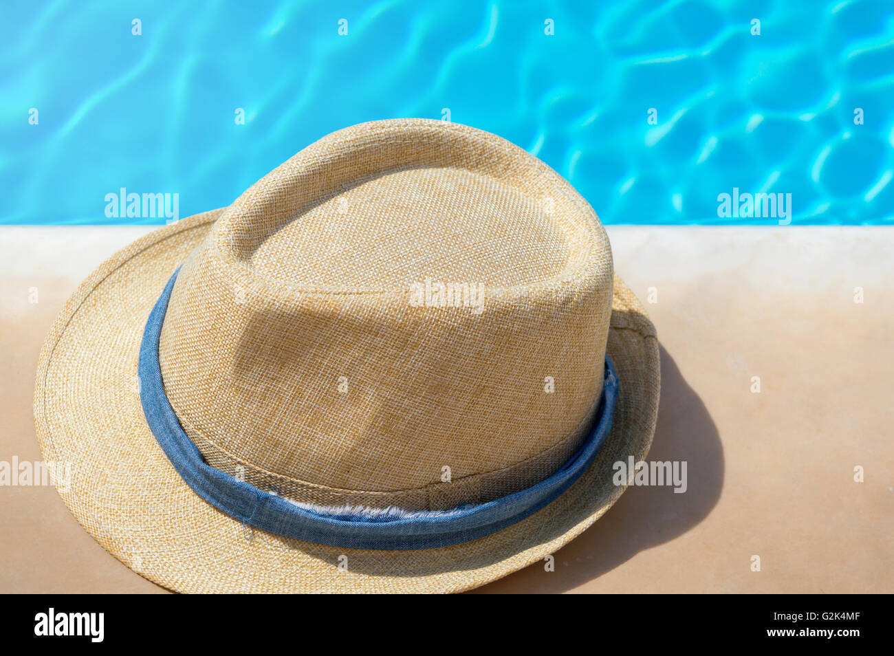Straw hat with blue band by the pool Stock Photo