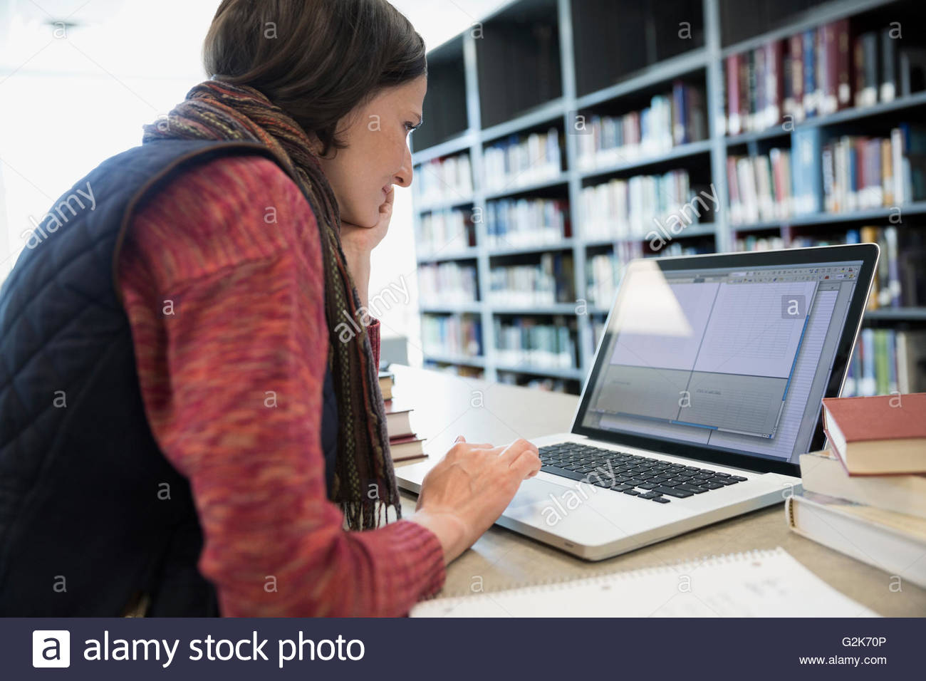 Adult education student researching at laptop in library Stock Photo