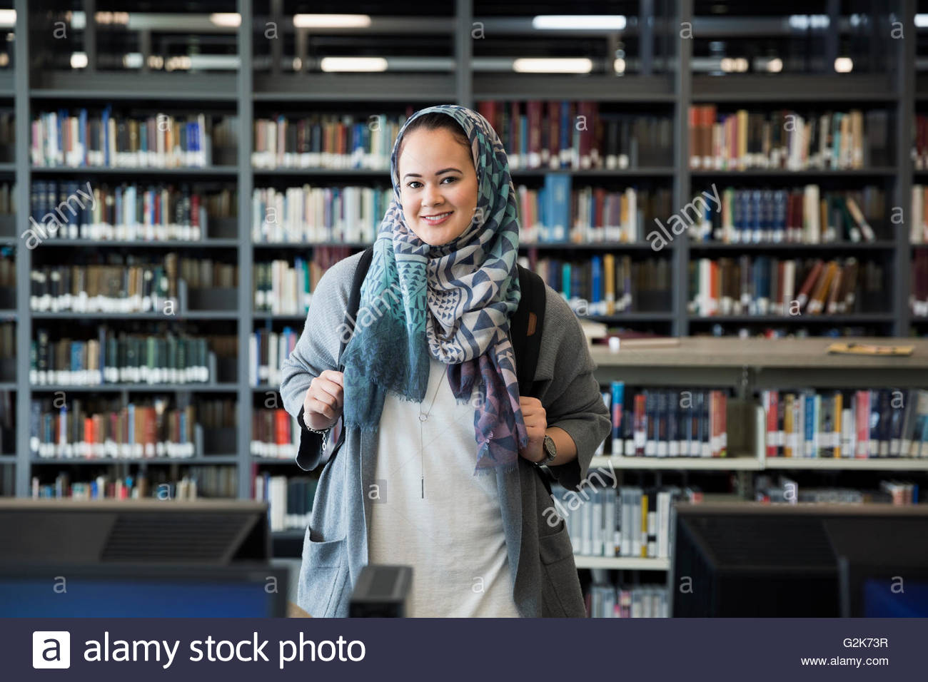 Portrait smiling college student wearing hijab in library Stock Photo