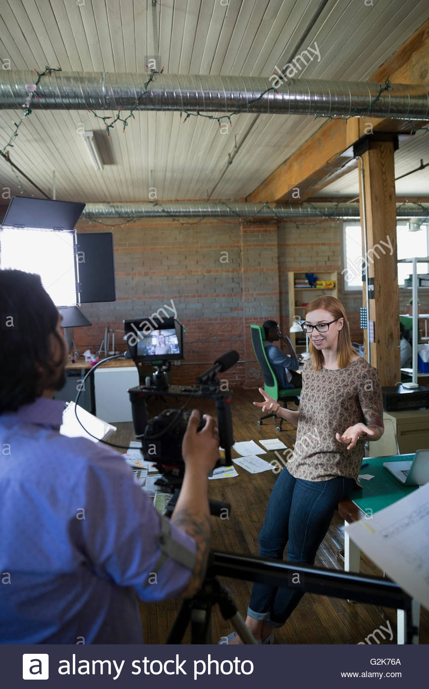 Cameraman filming creative businesswoman for tutorial Stock Photo