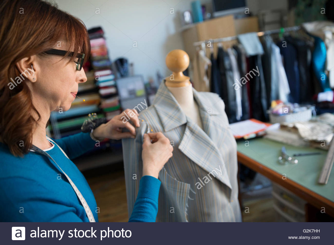 Dressmaker pinning suit on dressmakers model Stock Photo