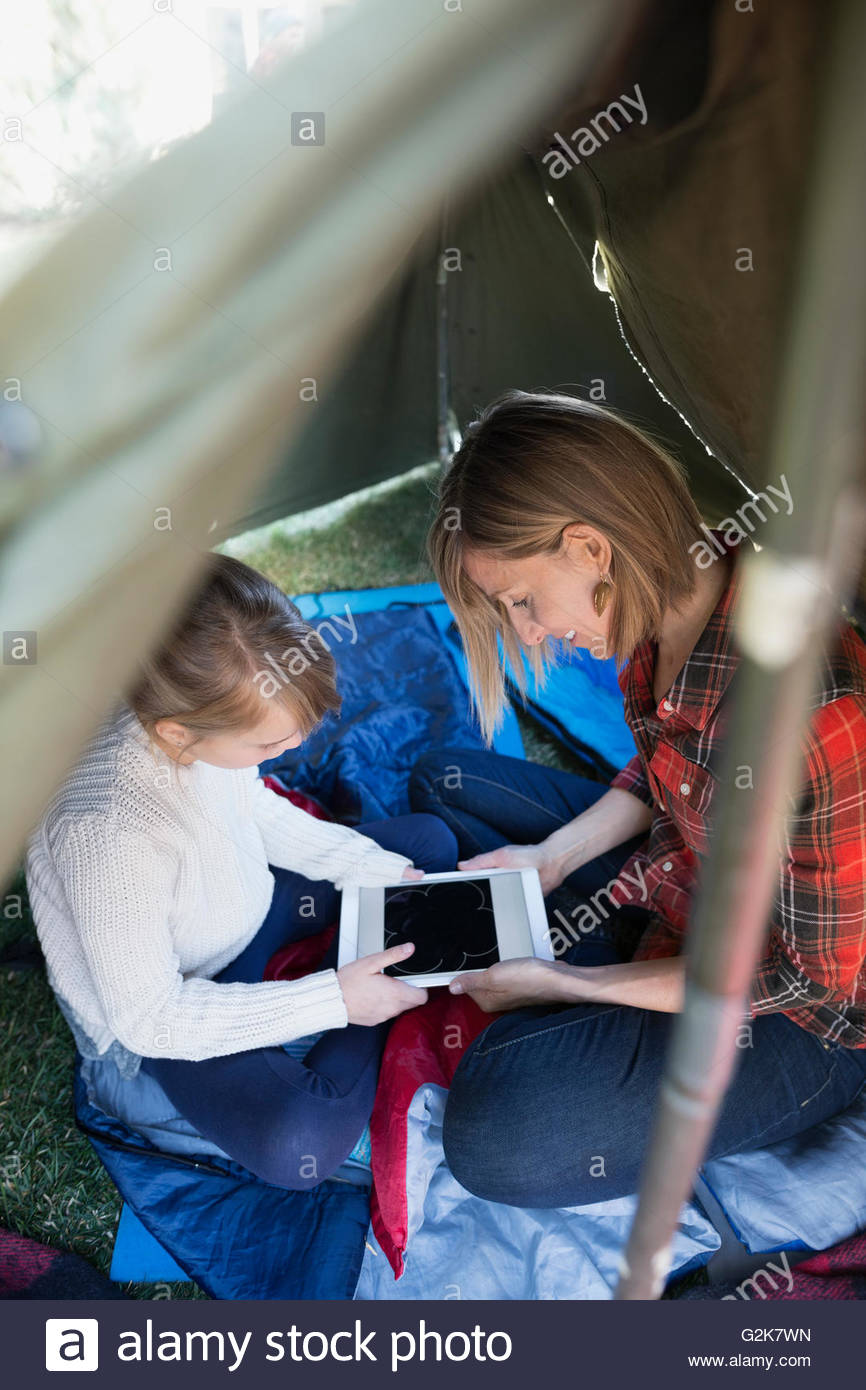 Mother and daughter playing game on digital tablet in tent Stock Photo