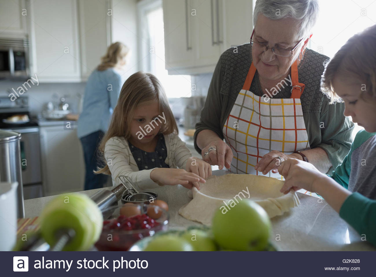 Grandmother and grandchildren baking apple pie in kitchen Stock Photo