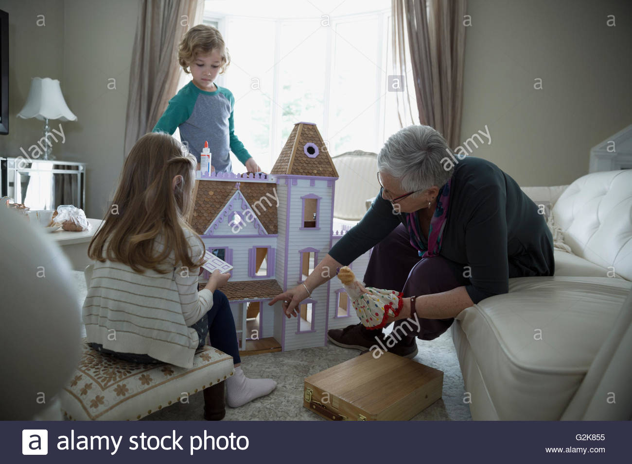 Grandmother and grandchildren playing with dollhouse Stock Photo