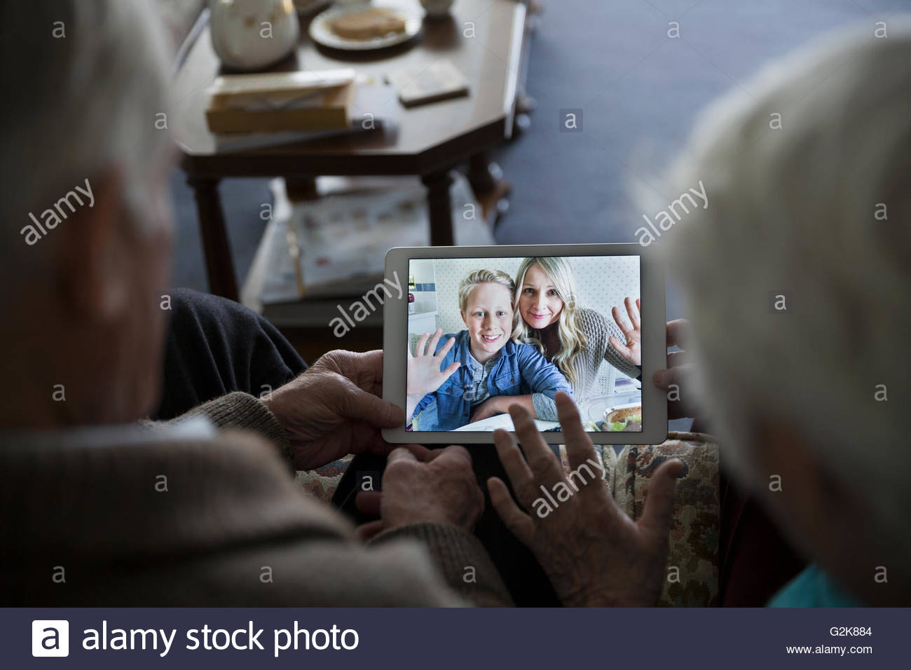 Senior couple video chatting with daughter and grandson on digital tablet Stock Photo