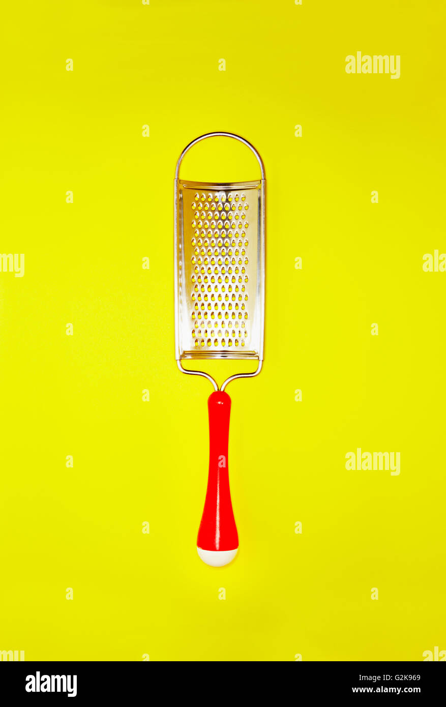 small metal grater on a bright yellow background Stock Photo