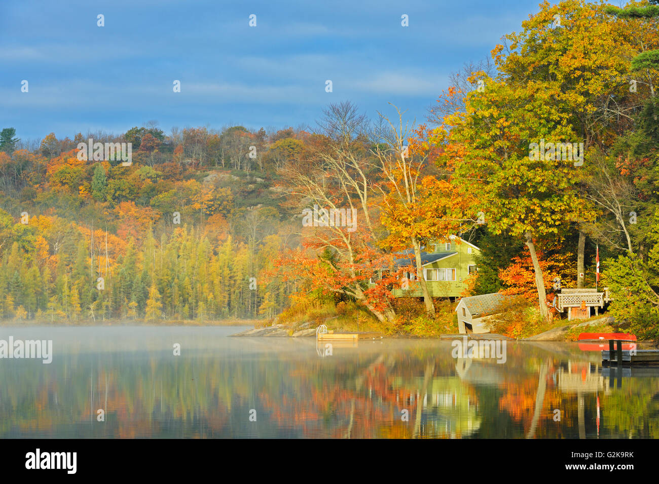 Fog on horseshoe lake in autumn with cottage hires stock photography