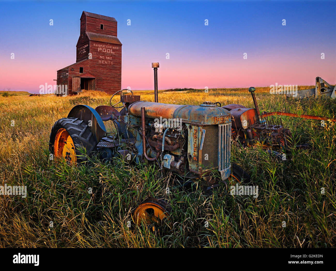 Grain elevator with old tractor at dawn Bents Saskatchewan Canada Stock
