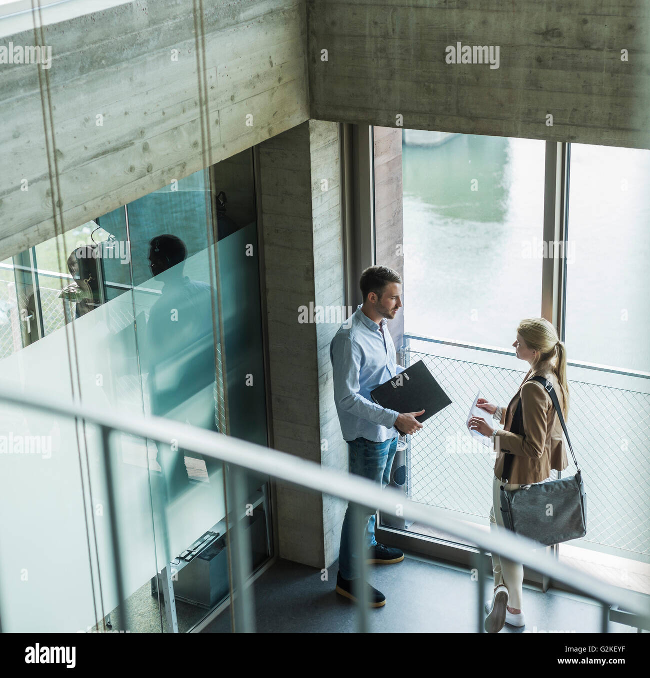 Two colleagues in office talking at the window Stock Photo - Alamy