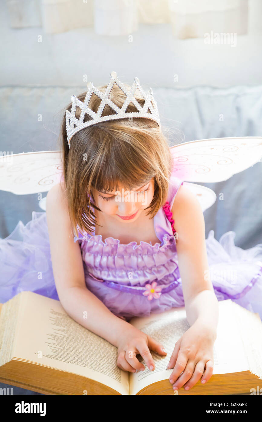 Little girl dressed up as fairy queen reading book Stock Photo Alamy