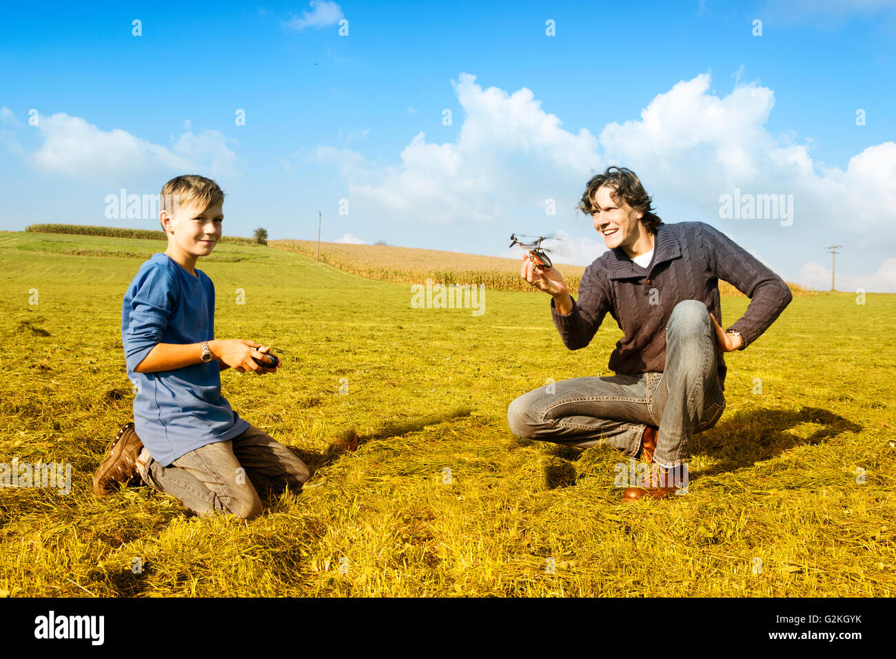 Father and son with remote-controlled helicopter in meadow Stock Photo