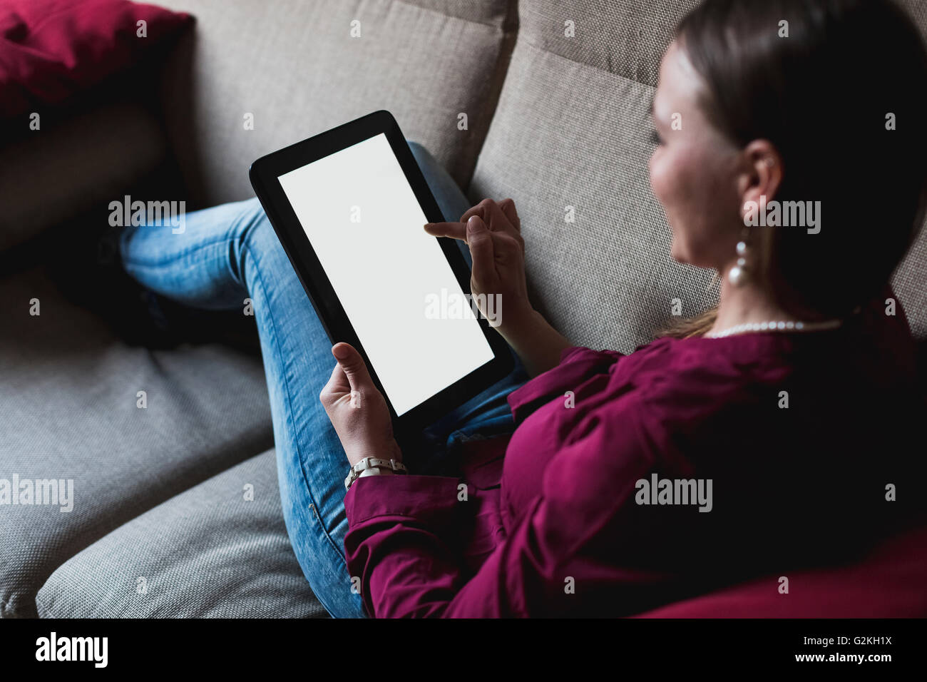 Young woman sitting on couch using digital tablet Stock Photo - Alamy