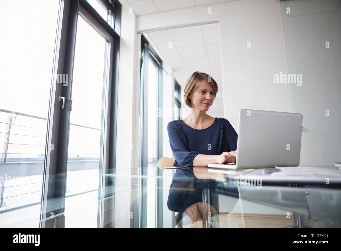 Businesswoman working on laptop at office desk Stock Photo