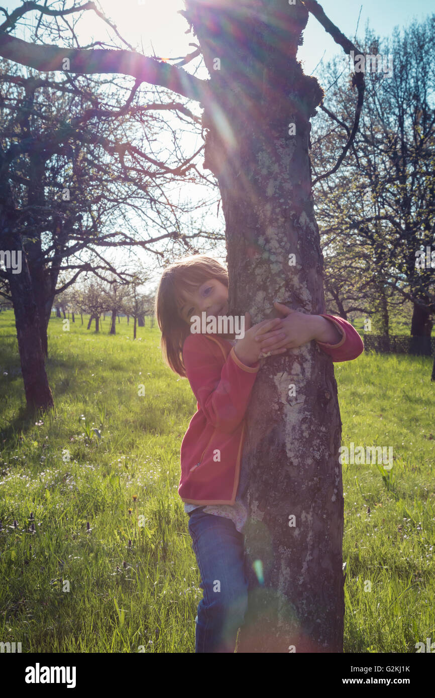 Portrait of smiling little girl embracing tree Stock Photo - Alamy