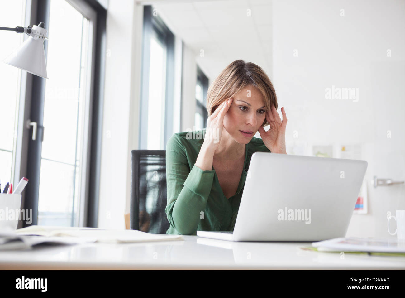 Concentrated businesswoman working on laptop at office desk Stock Photo
