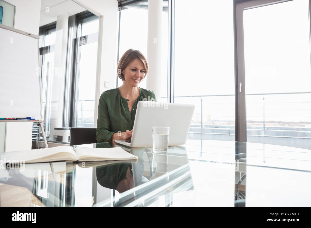 Smiling businesswoman working on laptop at office desk Stock Photo