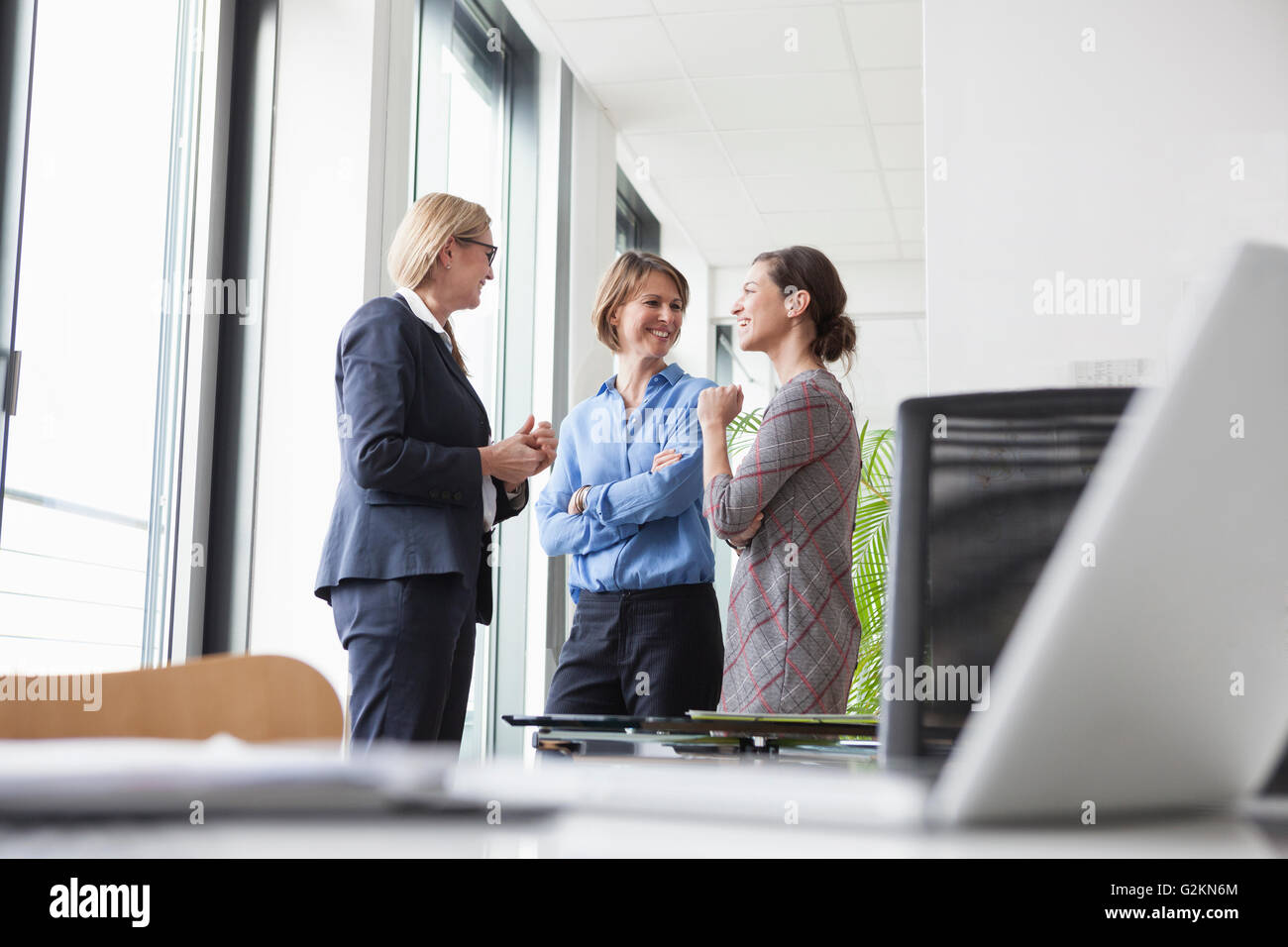 Three businesswomen talking at the window Stock Photo - Alamy