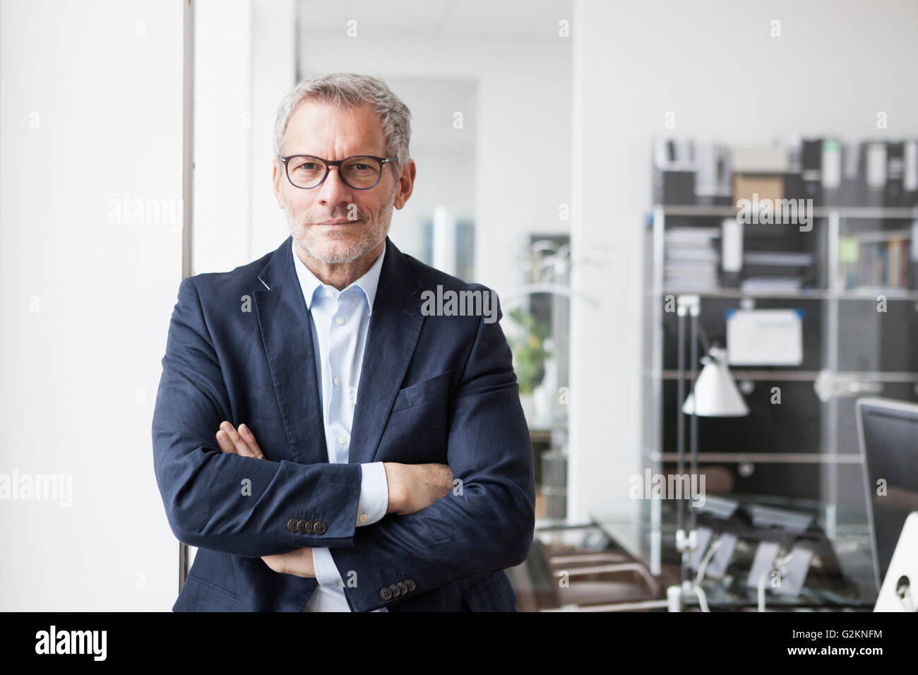 Successful businessman standing in his office with arms crossed Stock ...