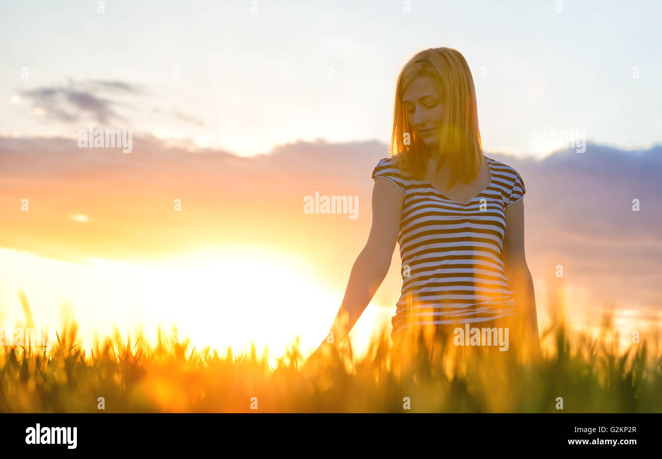 Beauty Girl Outdoors enjoying nature. Beautiful Teenage Model girl in white dress running on the Field, Sun Light. Glow Sun. Stock Photo