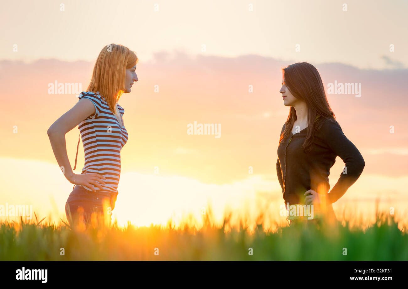 two beautiful girl in the sunset having an argue Stock Photo