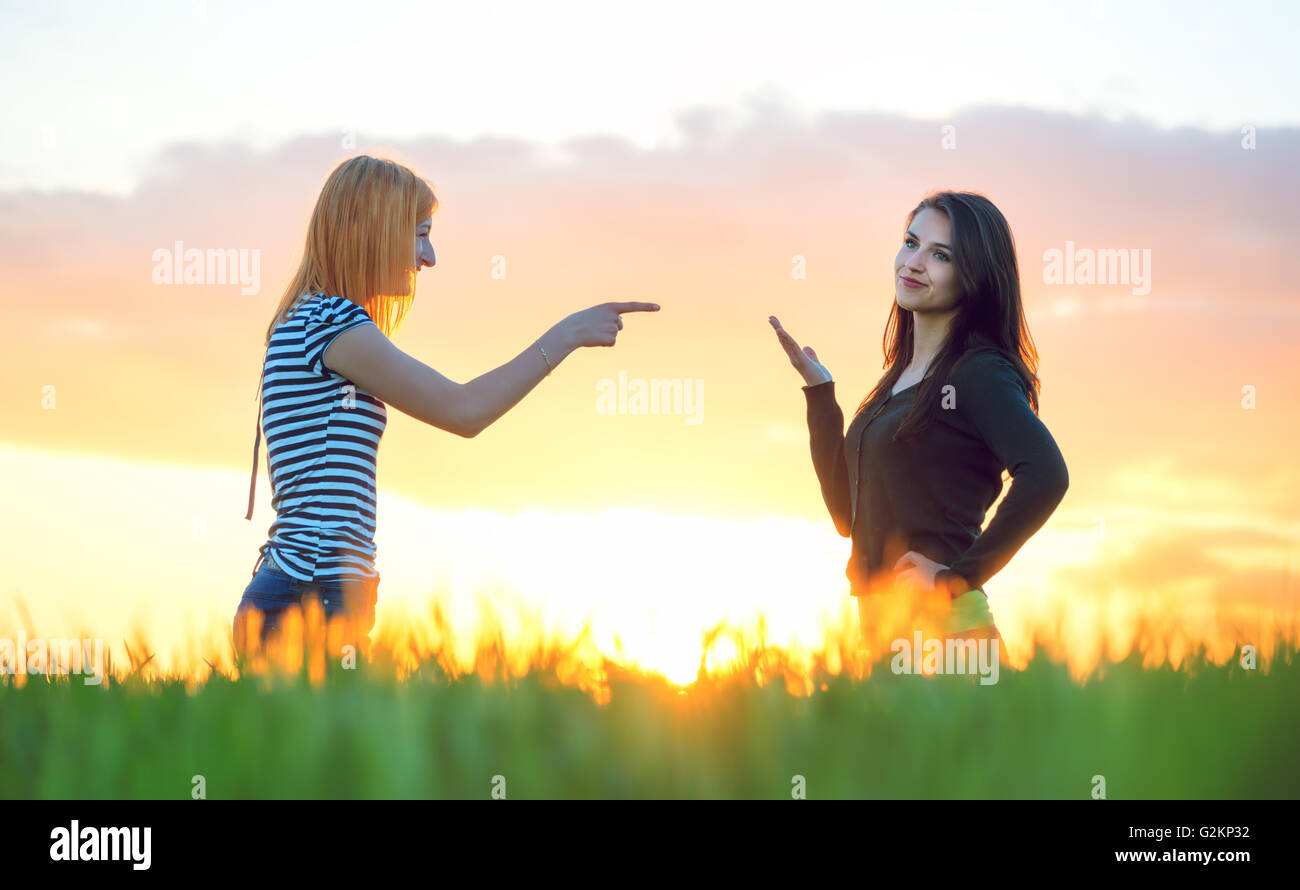 Two girls arguing pointing a finger and ignoring Stock Photo