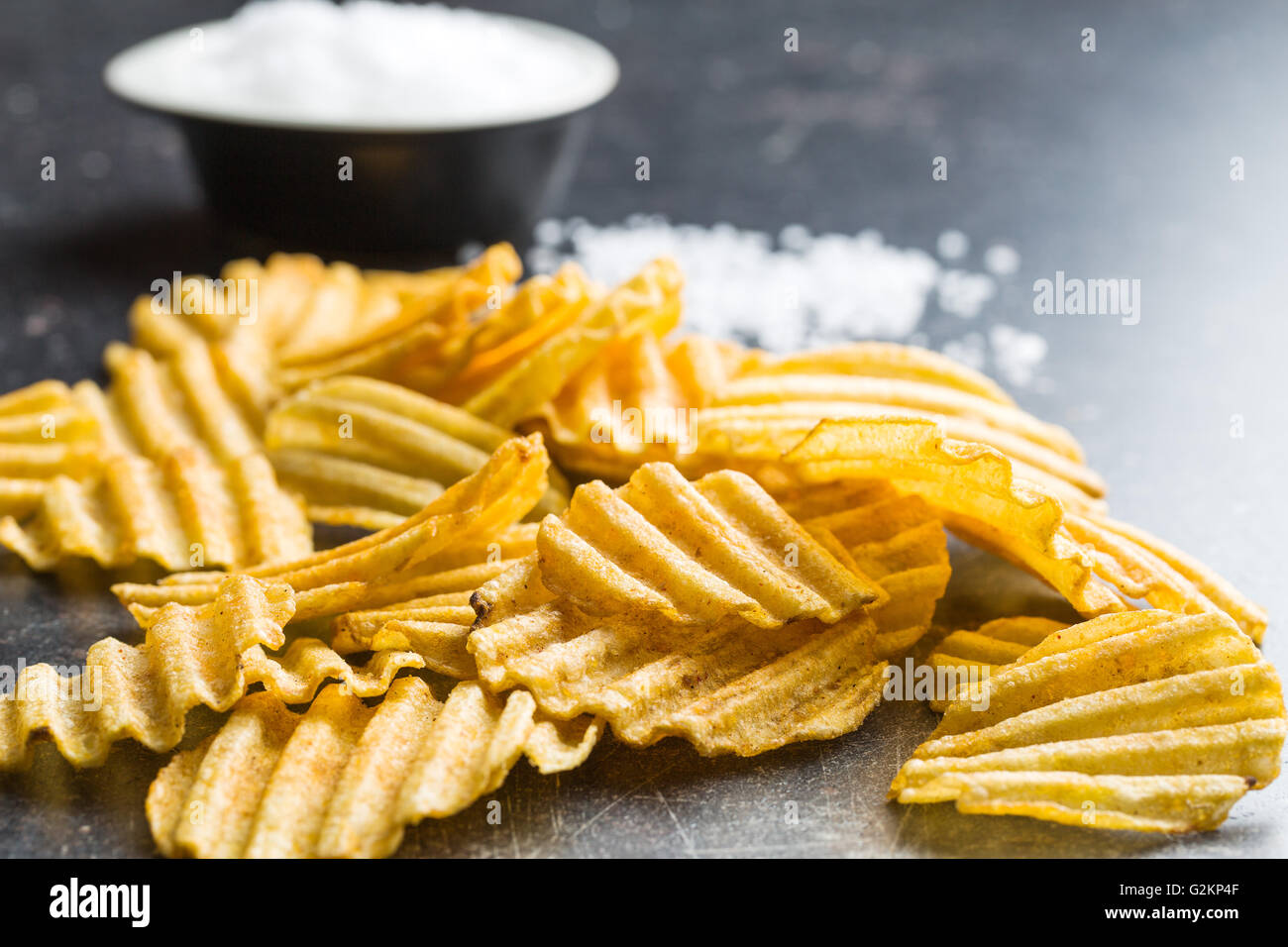 Crinkle cut potato chips on kitchen table. Tasty spicy potato chips