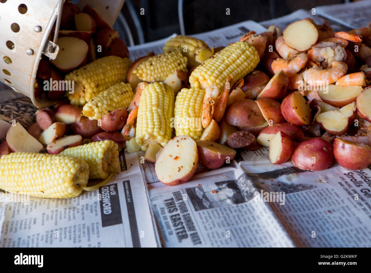 Low Country Boil with Shrimp, Corn, Sausage and Potatoes Being  Poured on Newspaper Stock Photo