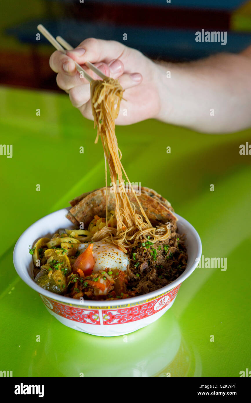Man Eating Bowl of Asian Noodles with Chopsticks Stock Photo