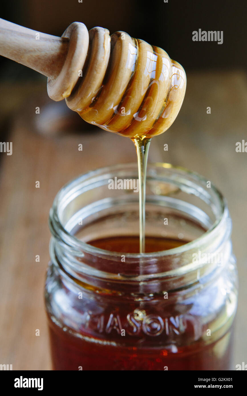 Honey Dripping From Wood Dipper into Jar Stock Photo - Alamy