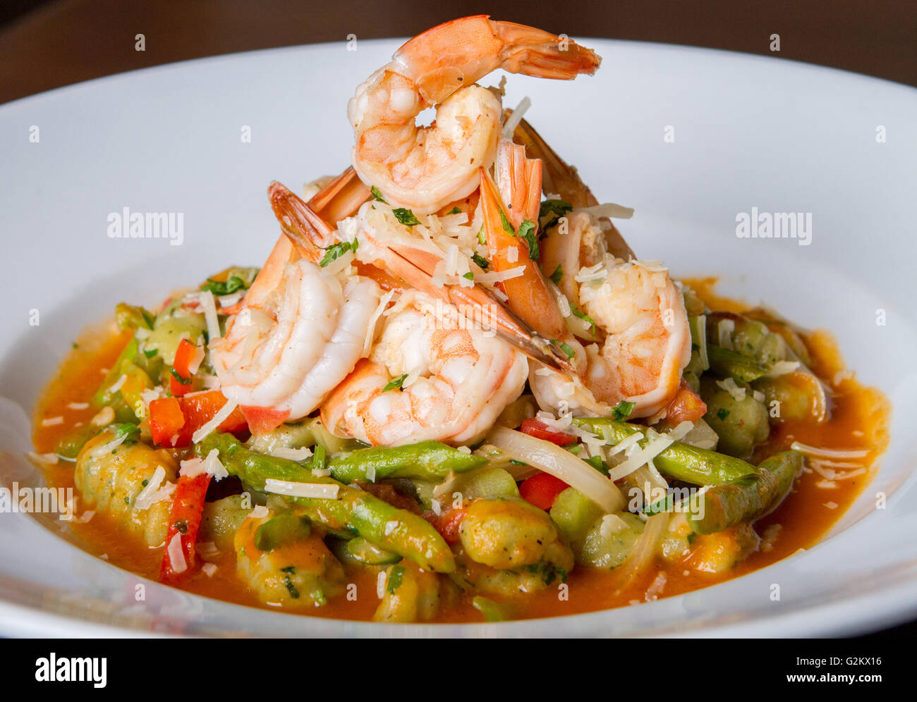 Pile of Shrimp on Bed of Assorted Vegetables in Red Sauce Stock Photo