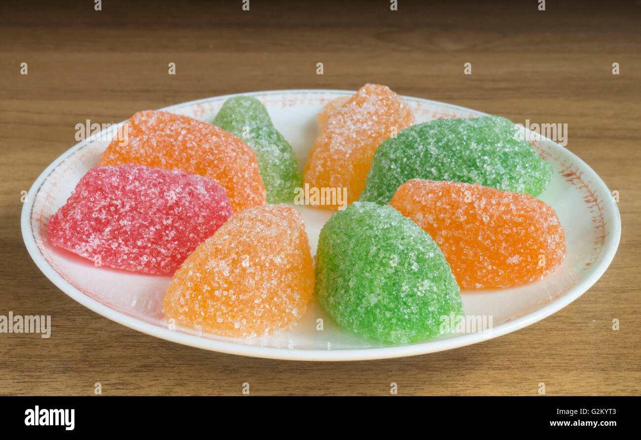 Sweet and tasty fruit jellies in round plate on wooden table Stock Photo