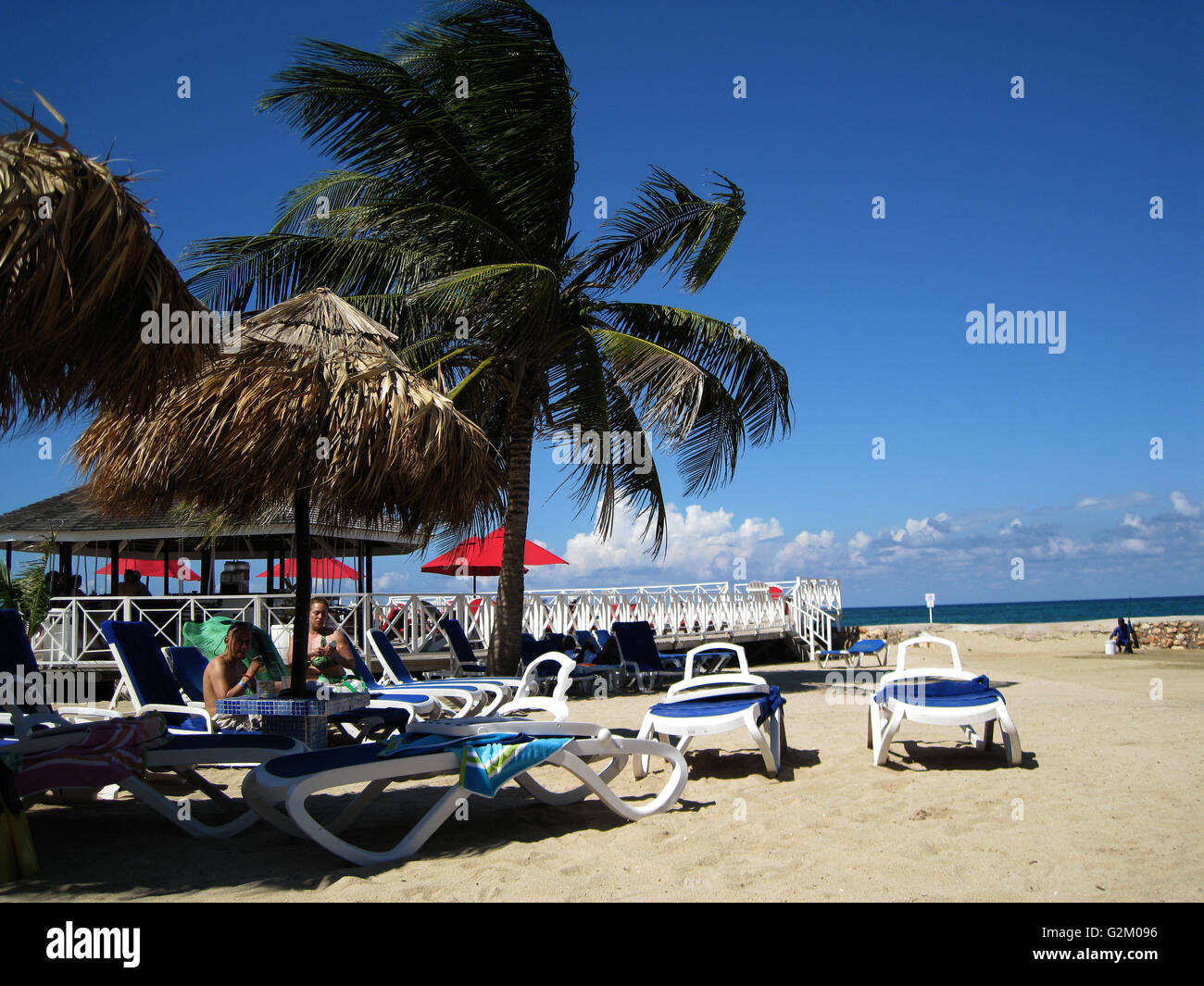 Beautiful sun lit warm Caribbean beach, golden sand and dramatic sky, Decameron Hotel, Runaway Bay, with coconut trees Stock Photo
