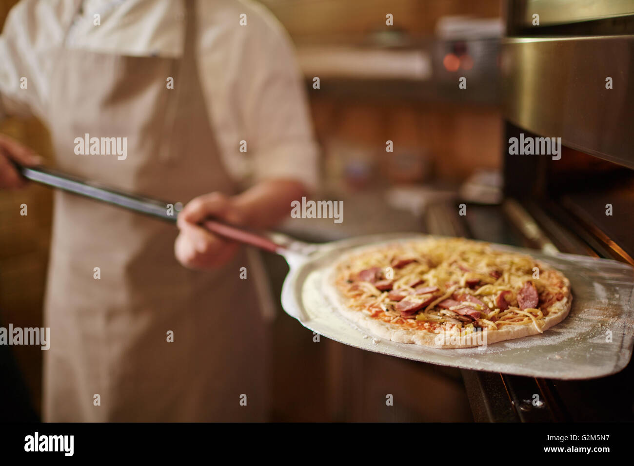 Putting pizza into oven Stock Photo Alamy