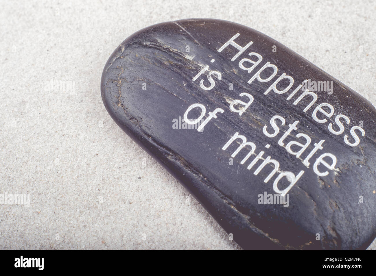 Zen picture of 'Happiness is a state of Mind' message engraved on a stone in the sand Stock Photo