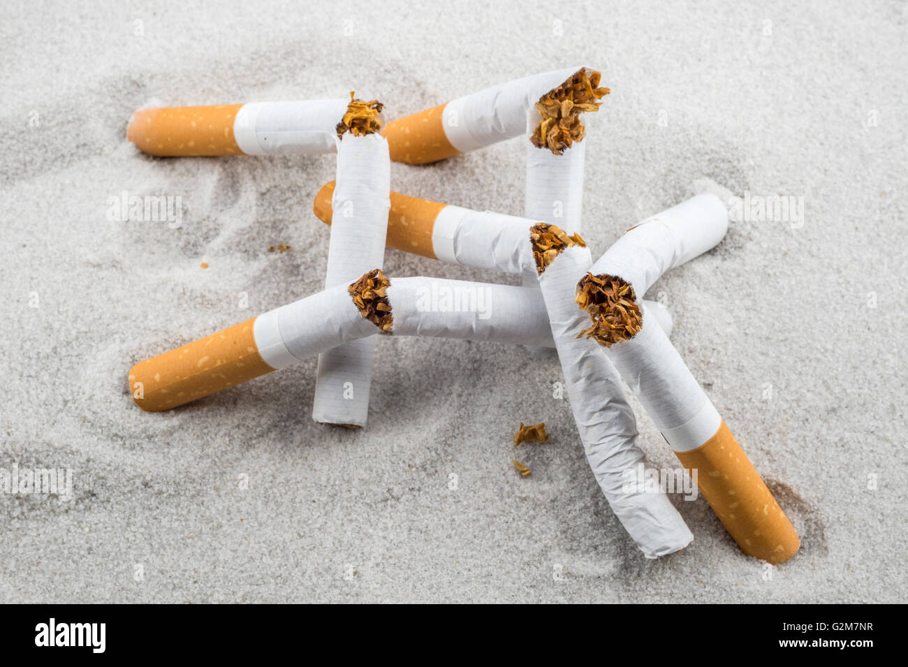 Quit Smoking - Broken unsmoked cigarettes in sand Stock Photo