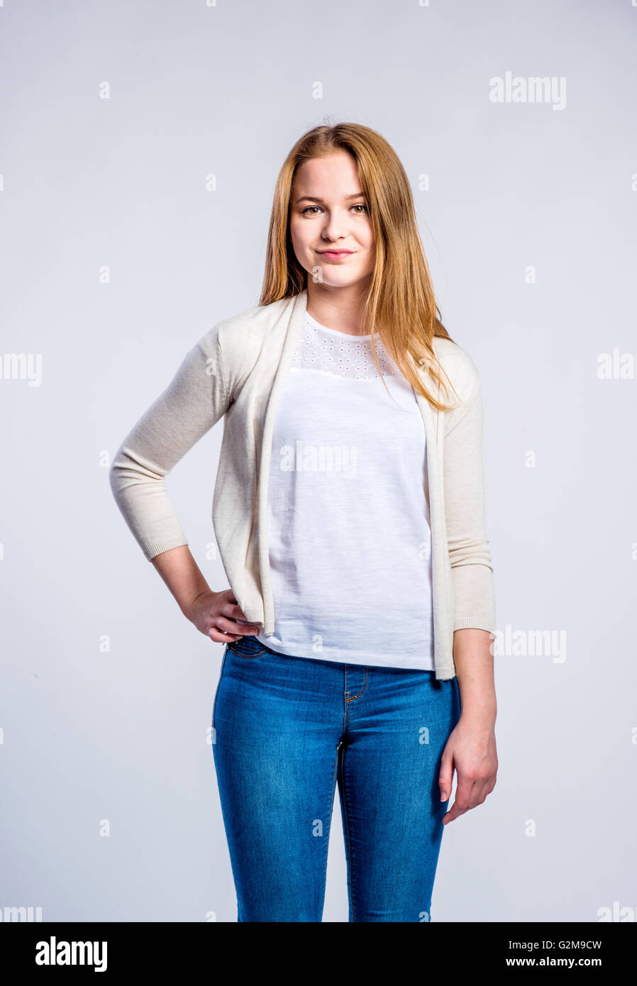 Teenage girl in jeans and beige cardigan, young woman, studio shot on gray  background Stock Photo - Alamy