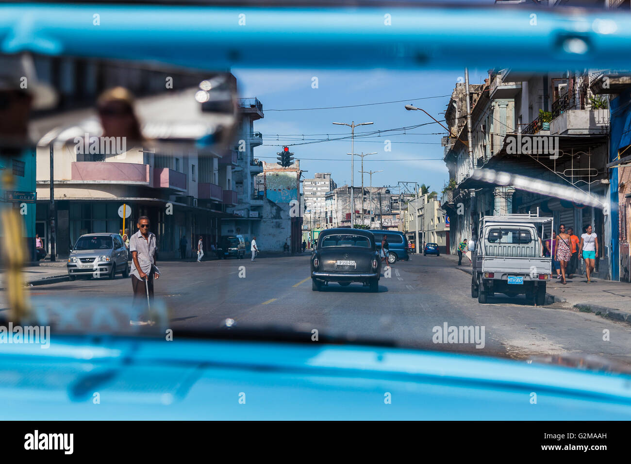 Looking through the windscreen of a blue & white classical Ford car as it travels through the streets of Havana. Stock Photo
