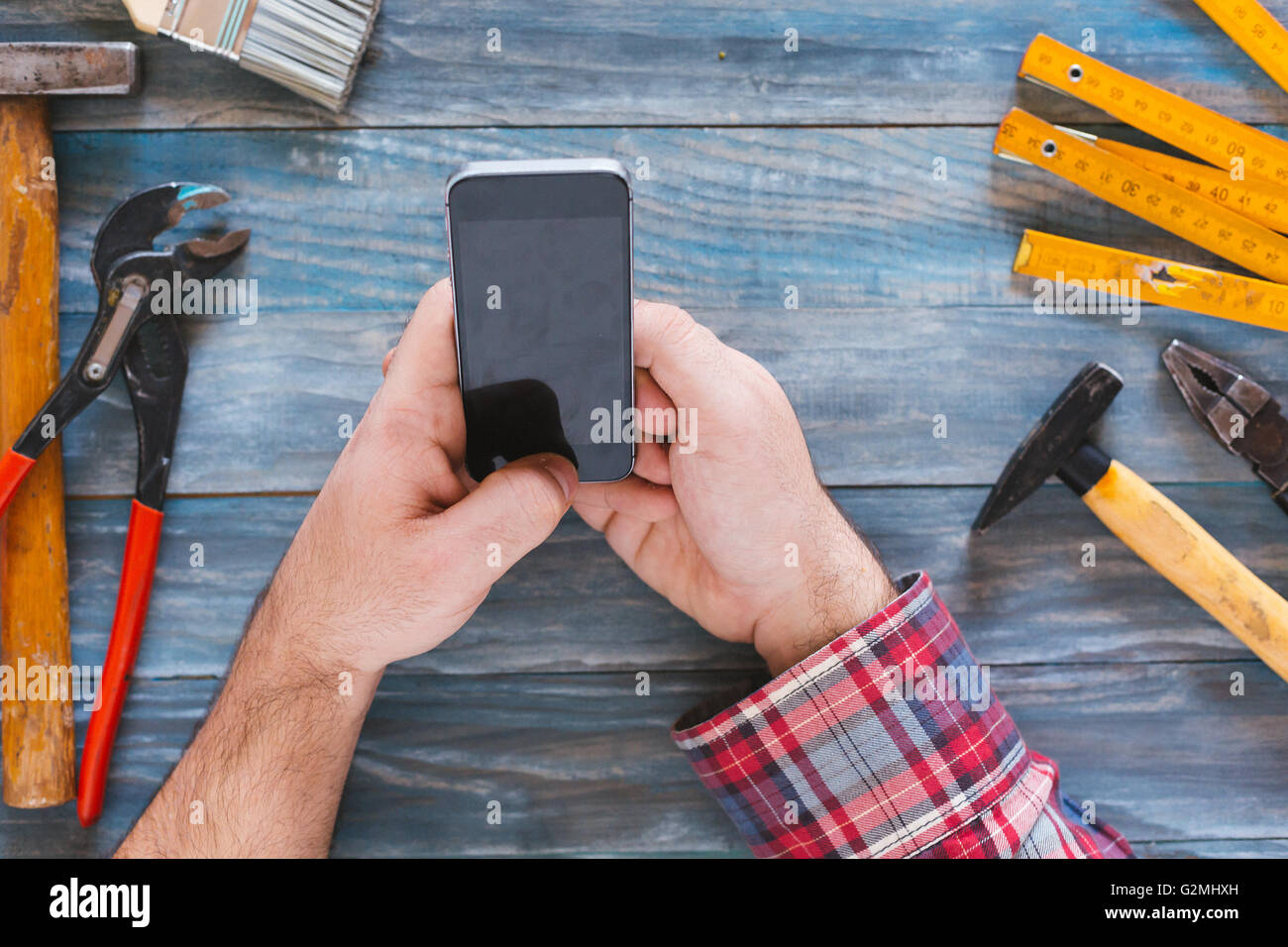 Man working on a DIY project with his phone, wood shavings and ...