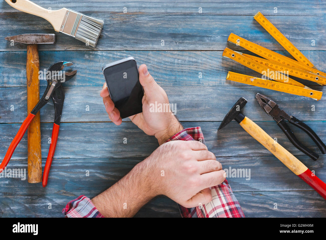 Man working on a DIY project with his phone, wood shavings and ...