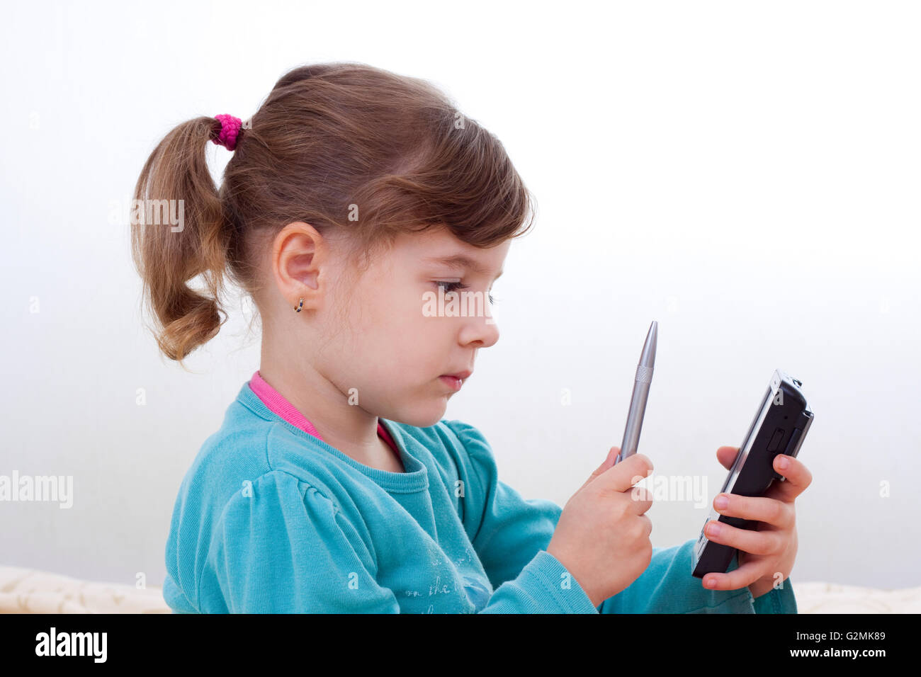 little girl using a palmtop with a silver pen Stock Photo