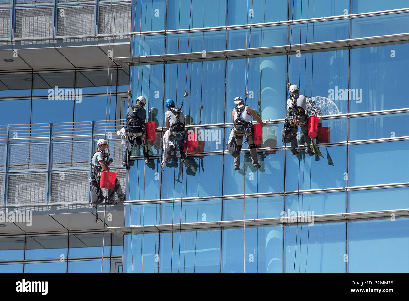 Group of window cleaners suspended from cables Stock Photo