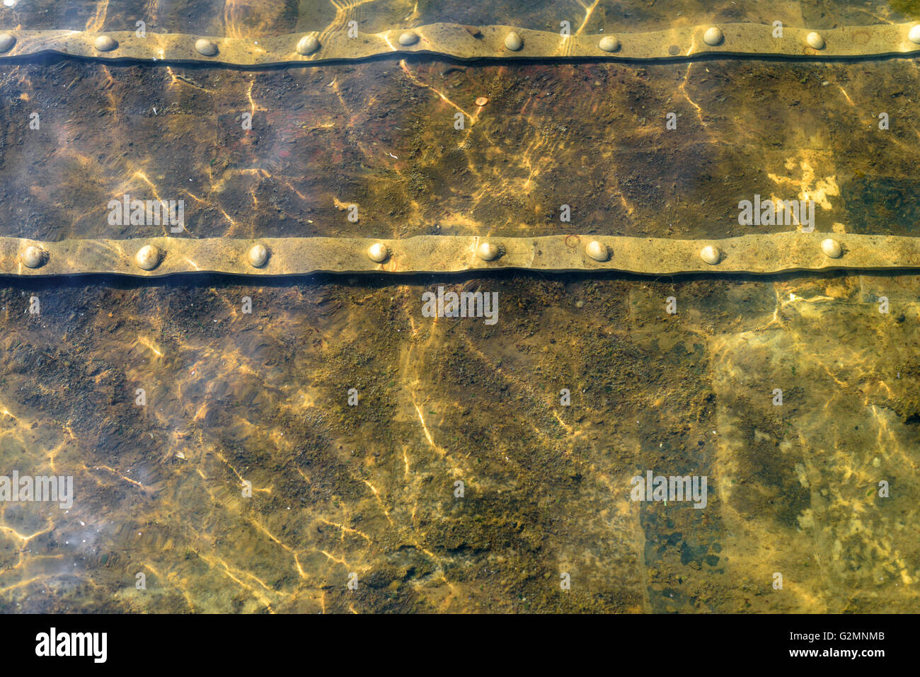 Stained metal underwater with a water wave pattern from natural movement and sunlight Stock Photo