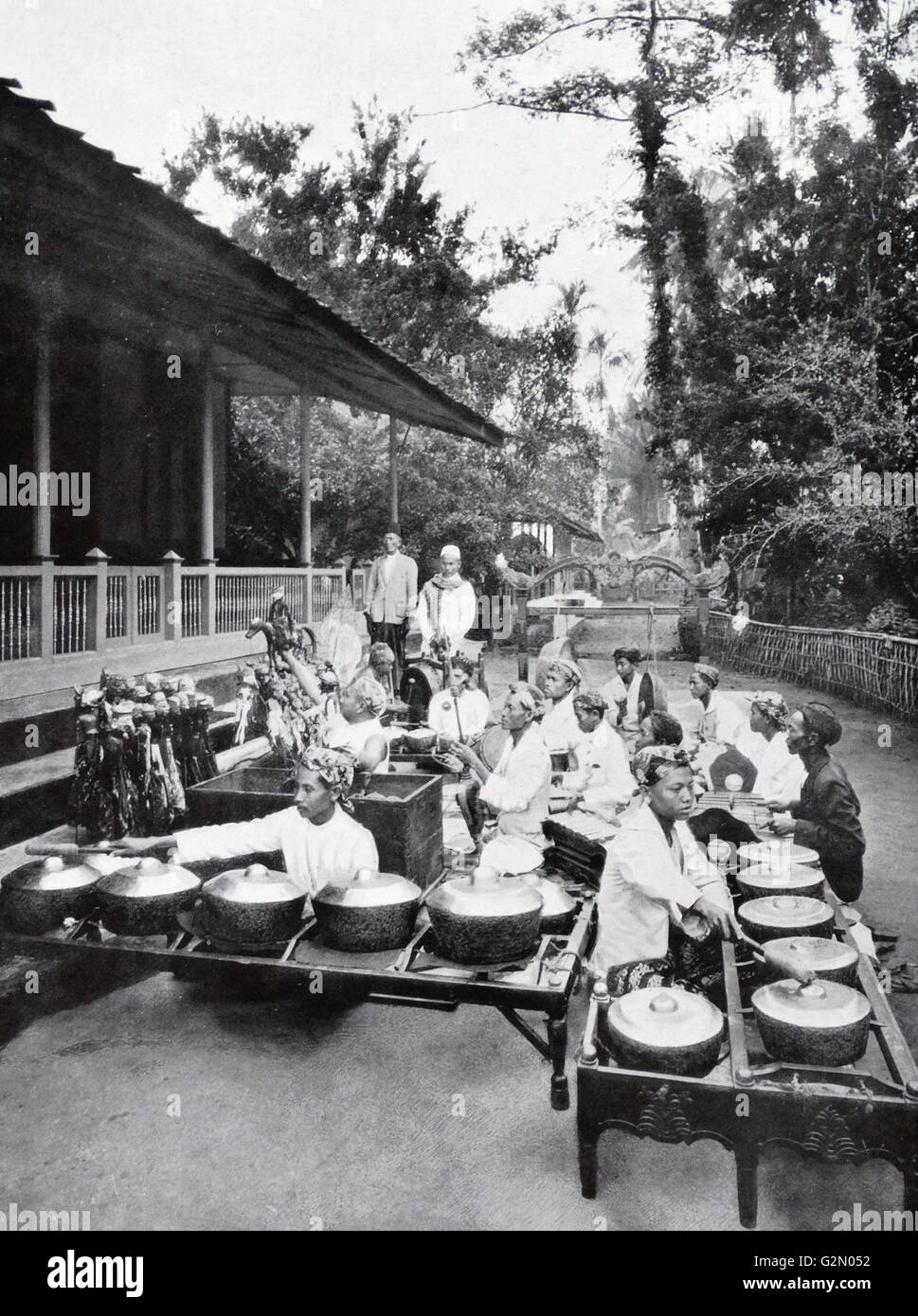 Photograph shows Indonesian Wayang-puppets and gamelan (Sundanese orchestra) sitting outside a village hut rehearsing. Dutch East Indies, known as modern Indonesia. Dated c1935. Stock Photo