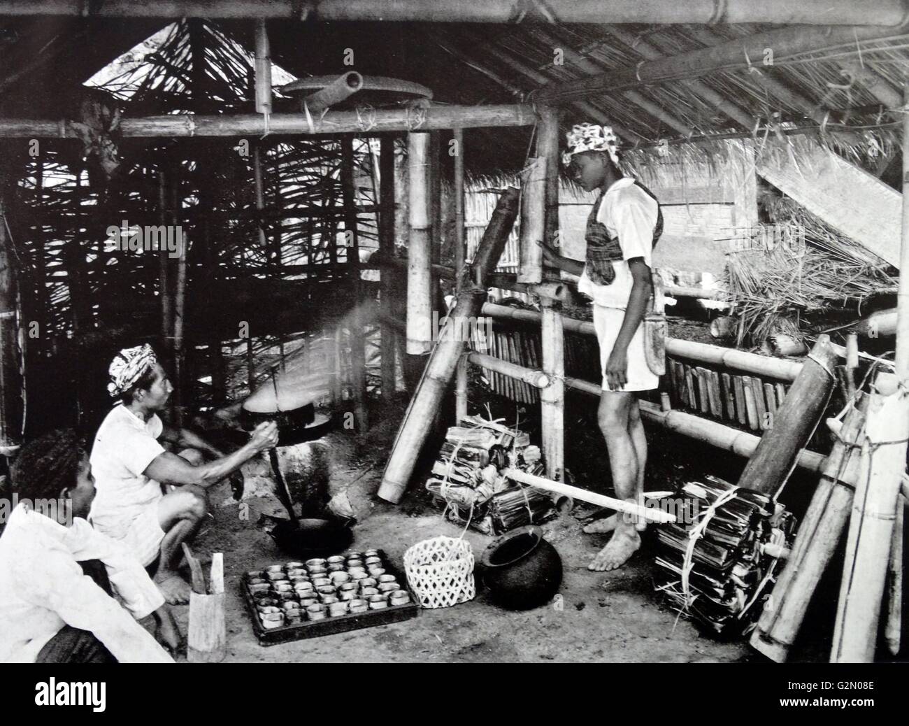 Photograph shows male figures in an Indonesian home cooking sugar spikes. Dutch East Indies, known as modern Indonesia. Dated c1935. Stock Photo