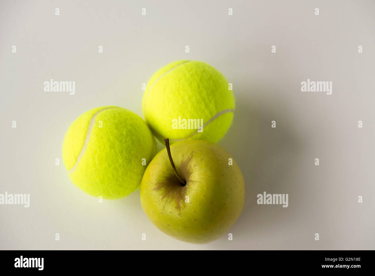 Golden apple with two tennis balls on white background Stock Photo