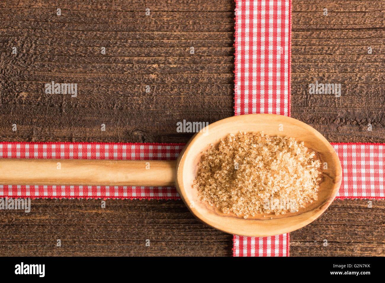 Rustic background with cane sugar on a wooden spoon on a rustic table. Stock Photo