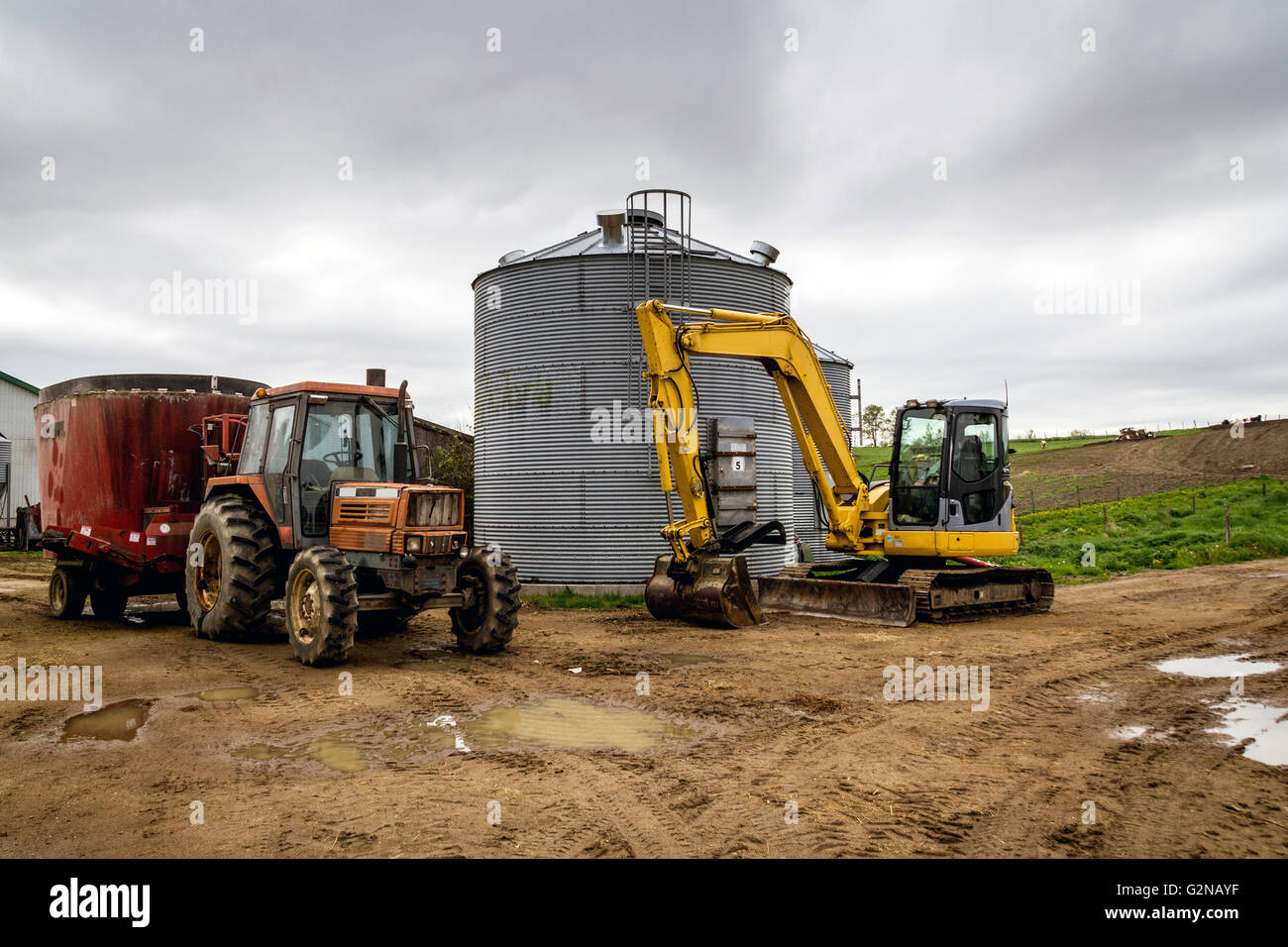 farming tractor and excavator in front of a silo Stock Photo
