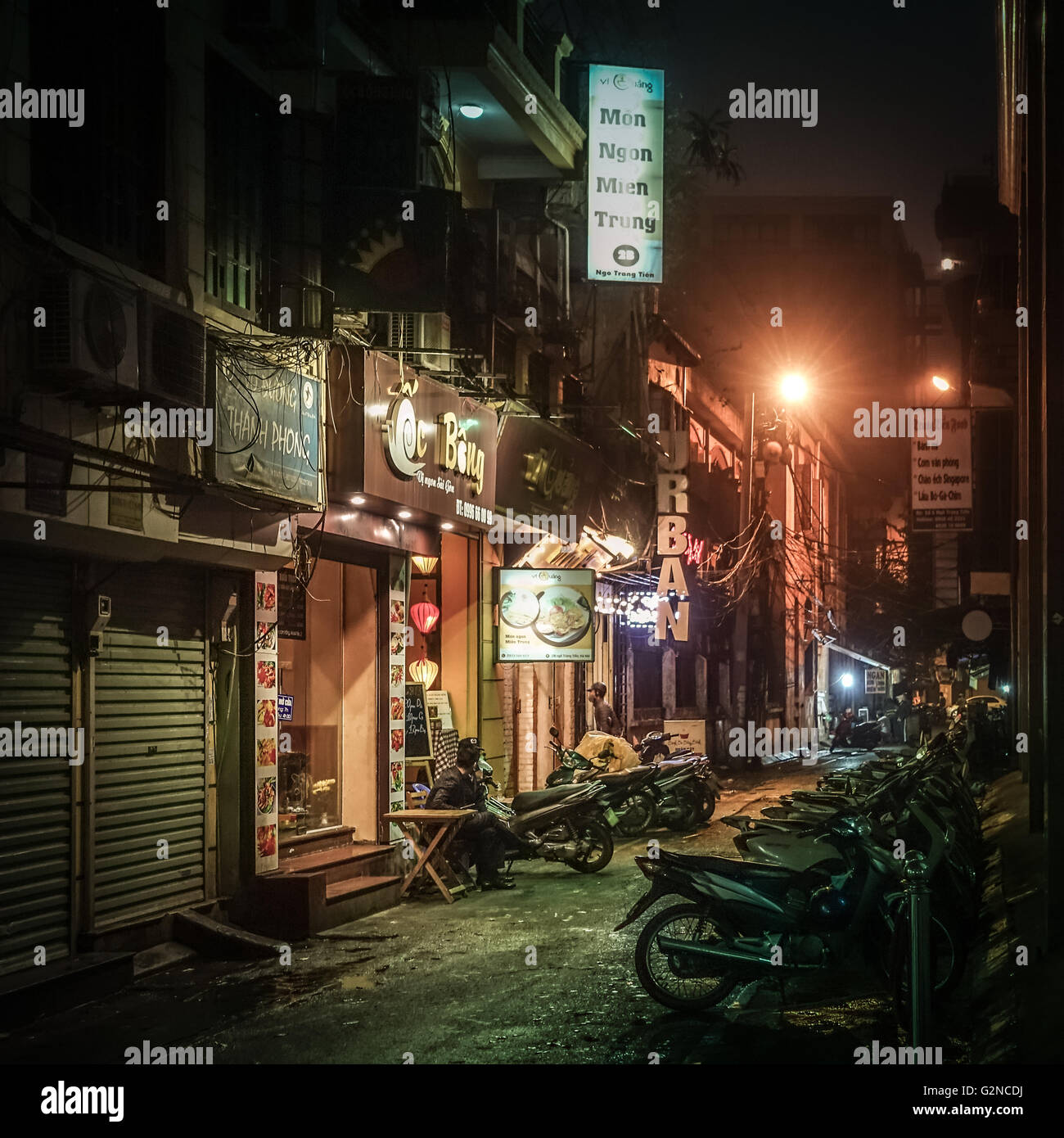 A typical side-street at night lined with mopeds at night in Hanoi, Vietnam Stock Photo