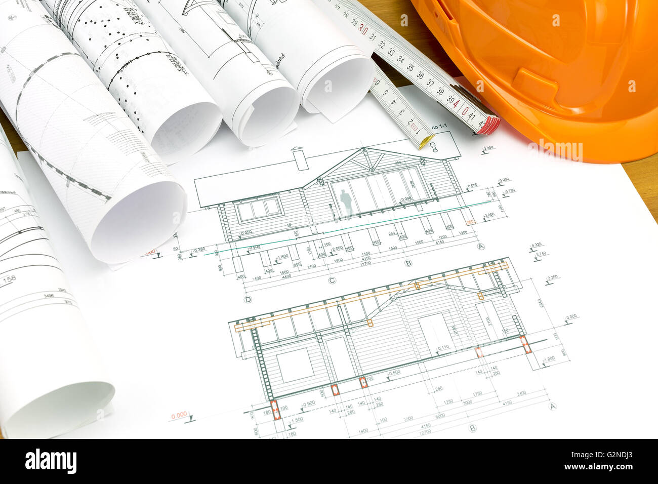 safety helmet with wooden ruler and blueprint rolls Stock Photo - Alamy